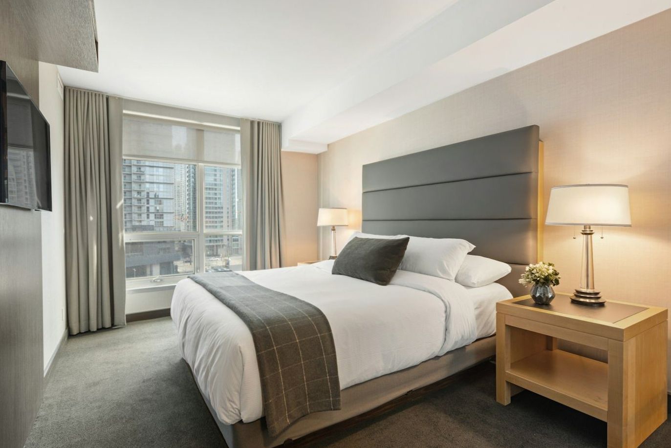 Standard hotel room with neatly made bed and muted eucalyptus textiles